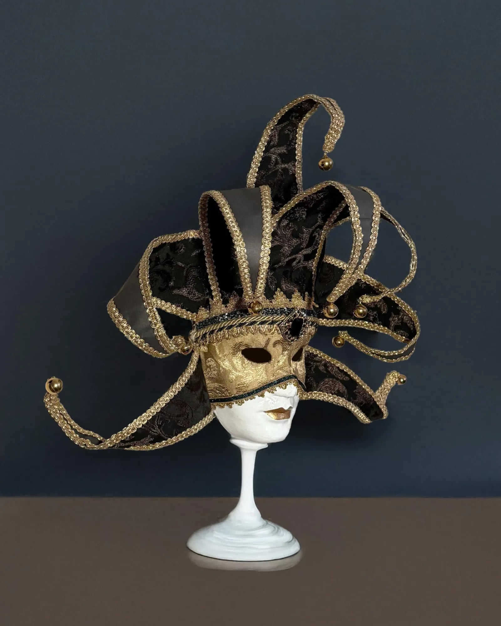 Black and Gold Luxury Jester, Venetian; Luxurious Fabric Mask on stand, handcrafted for cosplay, masquerade, and fantasy events.
