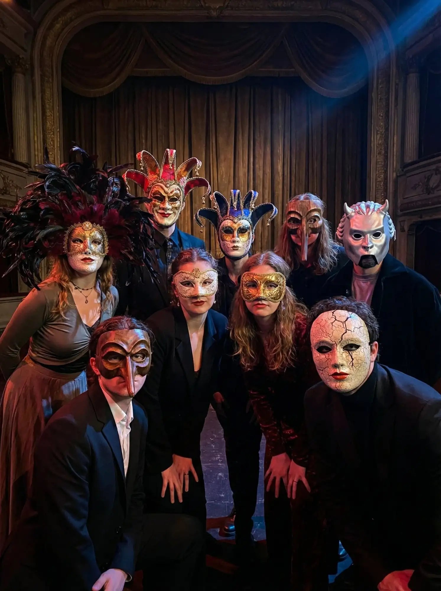 Black leather mask with intricate silver detailing and a dramatic red feather boa.