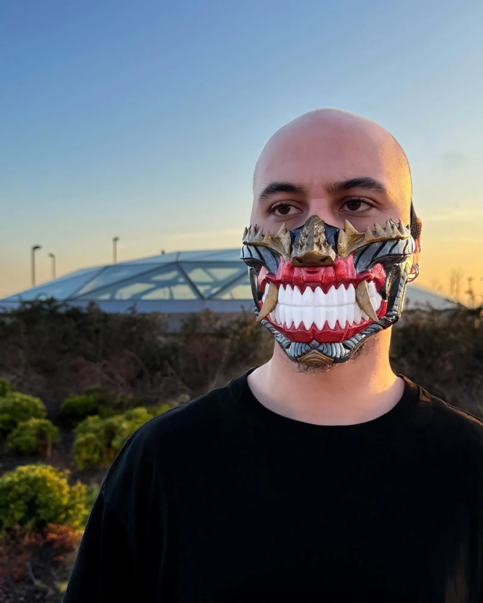 Dark Cyber Samurai Half Oni dark Onu demons mask with white teeth, handcrafted Venetian cosplay fantasy mask, worn by a person outdoors.