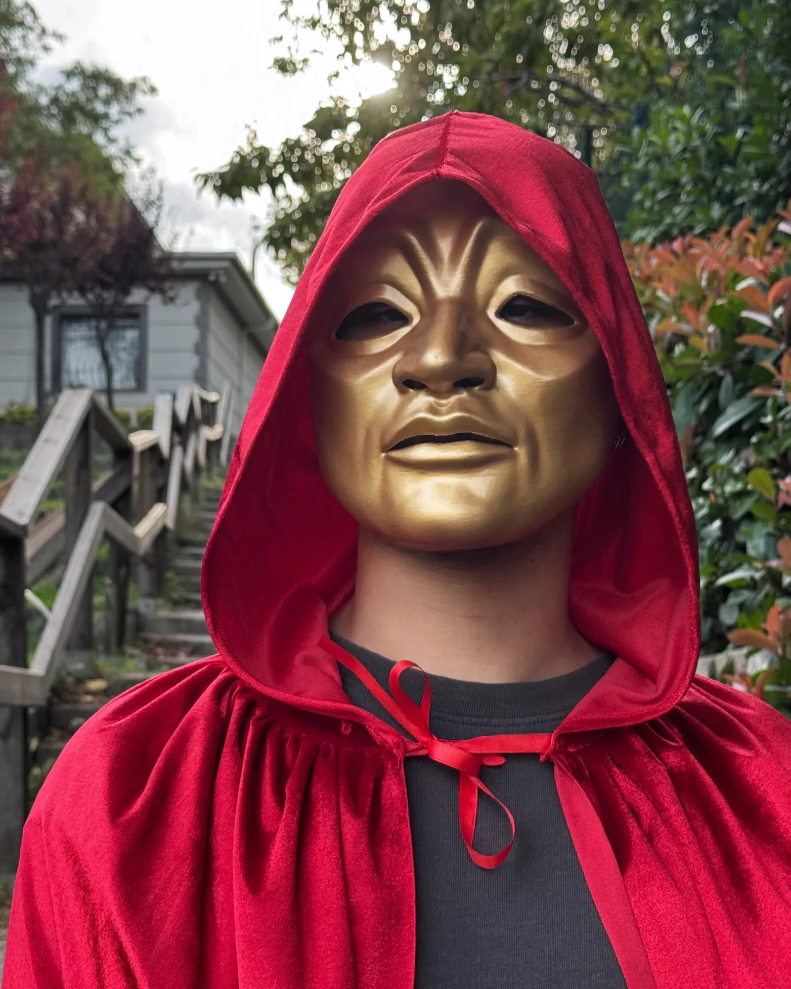 Person wearing Eyes Wide Shut Golden Red Cloak Judge mask, handcrafted Venetian style for cosplay and masquerade events.
