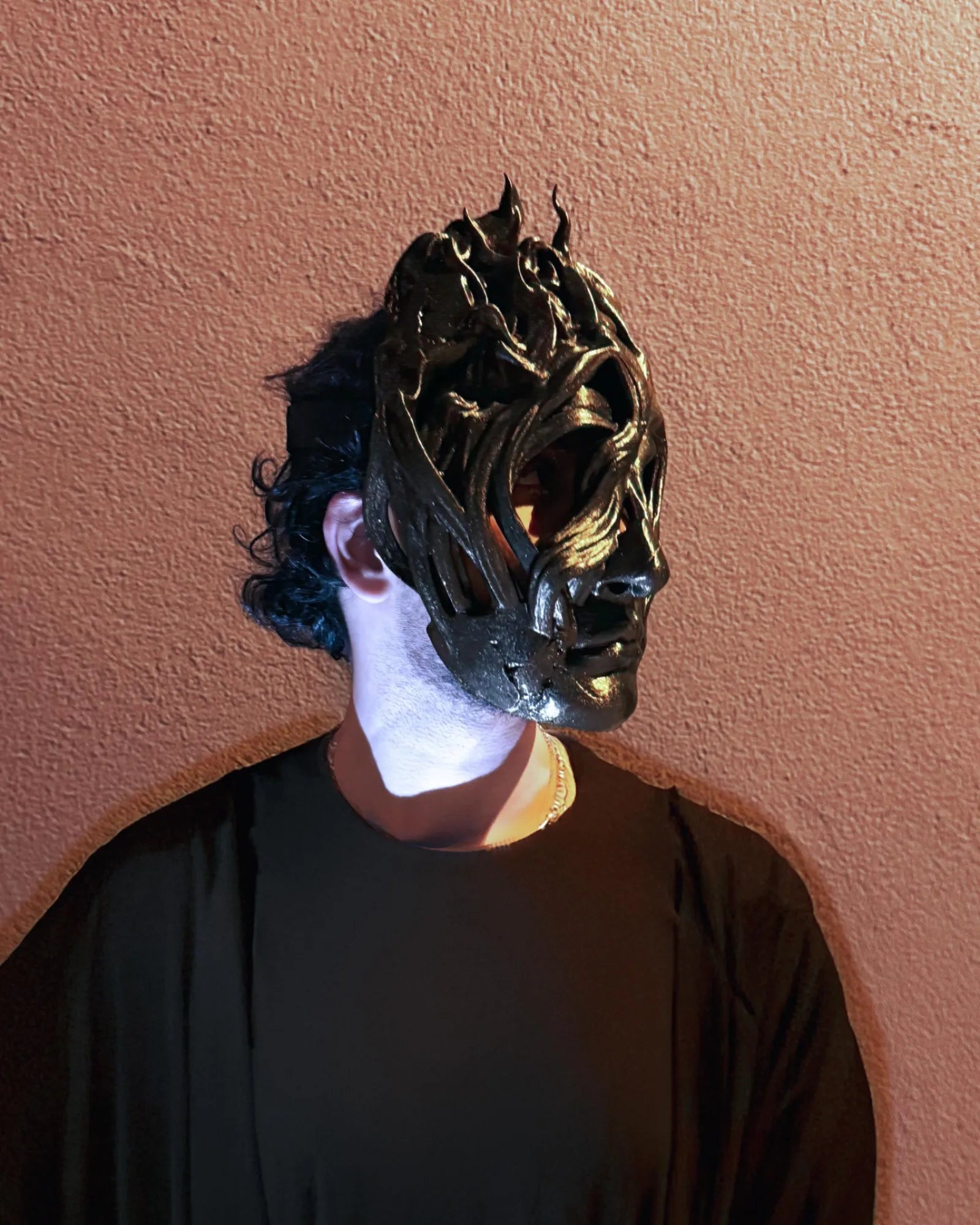 Person wearing handcrafted Mask of the Shadows - Dark venetian volatile head, shadow mask, suitable for cosplay and fantasy events.