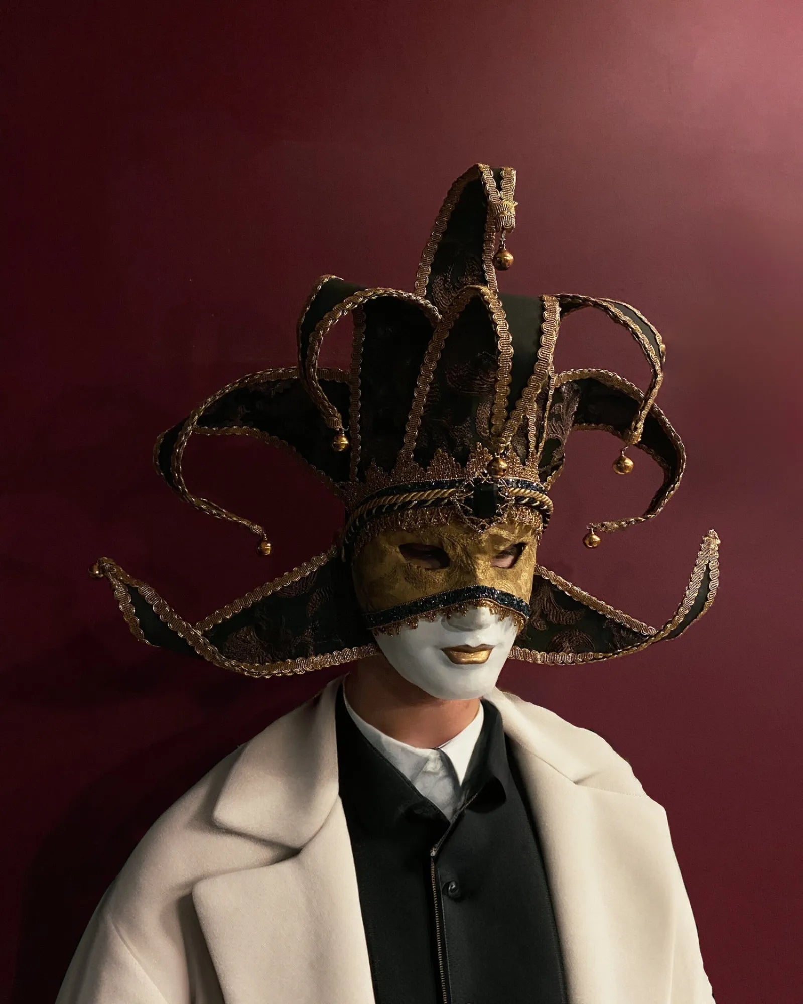 Person wearing Black and Gold Luxury Jester, Venetian; Luxurious Fabric Mask, handcrafted for masquerade, cosplay, or carnival.