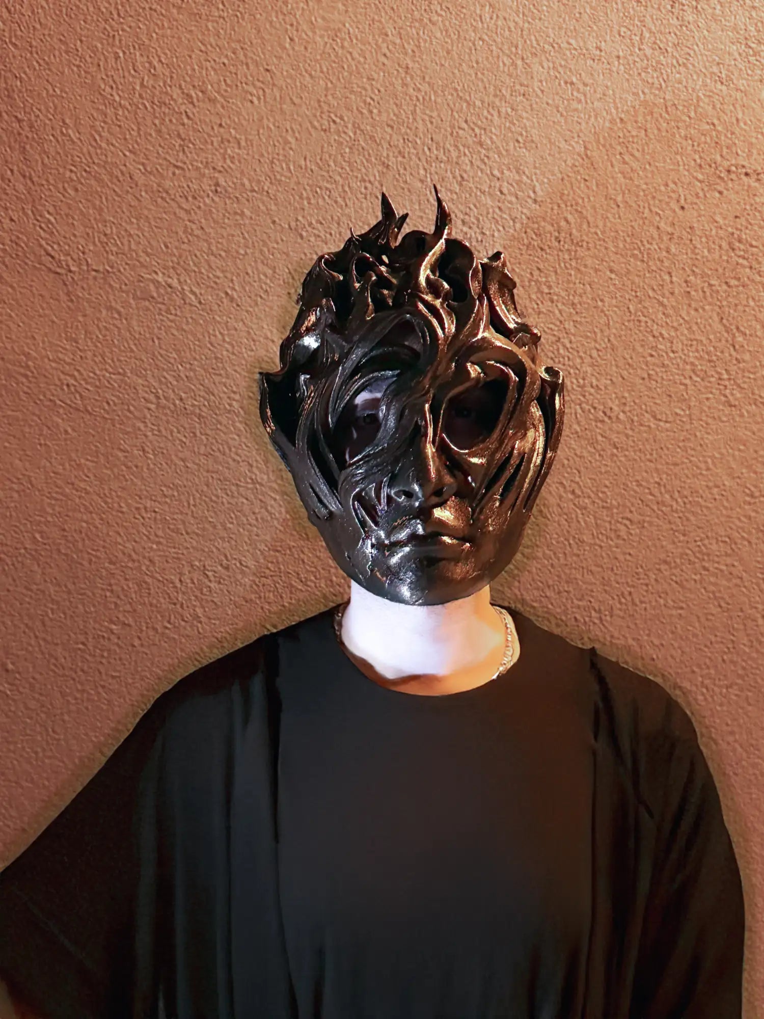 Black skull mask with intricate designs and a glossy finish.