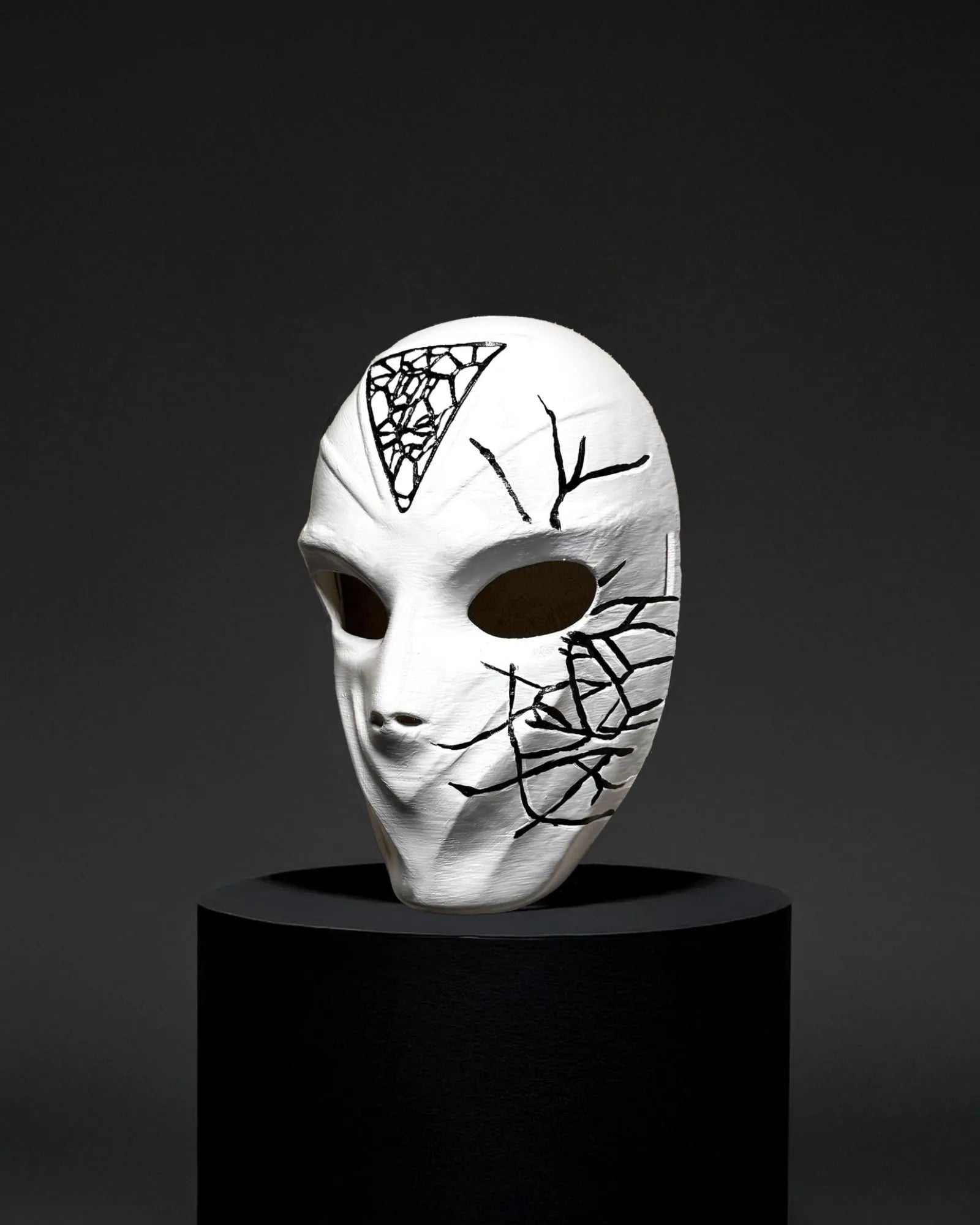Conspirator Venetian Black Crackle Pattern; Graffiti Style White Mask, handcrafted for cosplay and fantasy, on dark display.