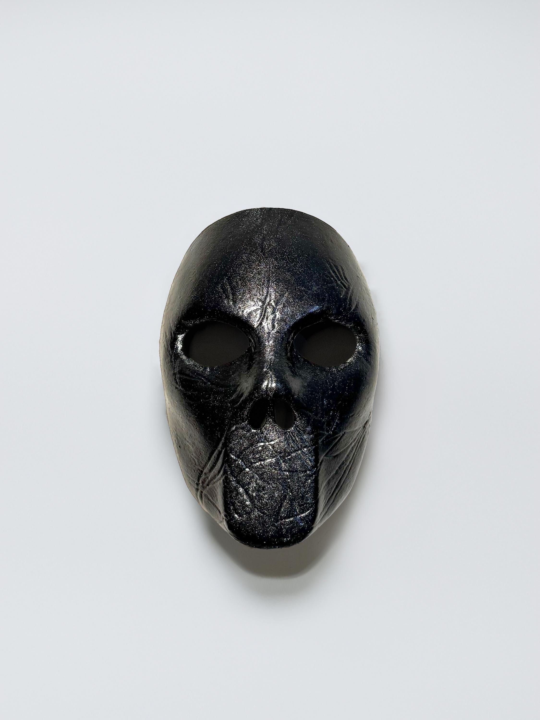 May include: A black mask with a textured surface and two eye holes.