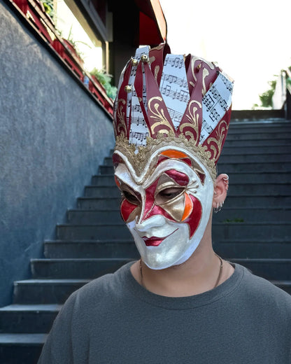 Joker Venetian Mask Iconic Techno Red; Colorful Rio Carnival handcrafted cosplay fantasy mask on a person outdoors.