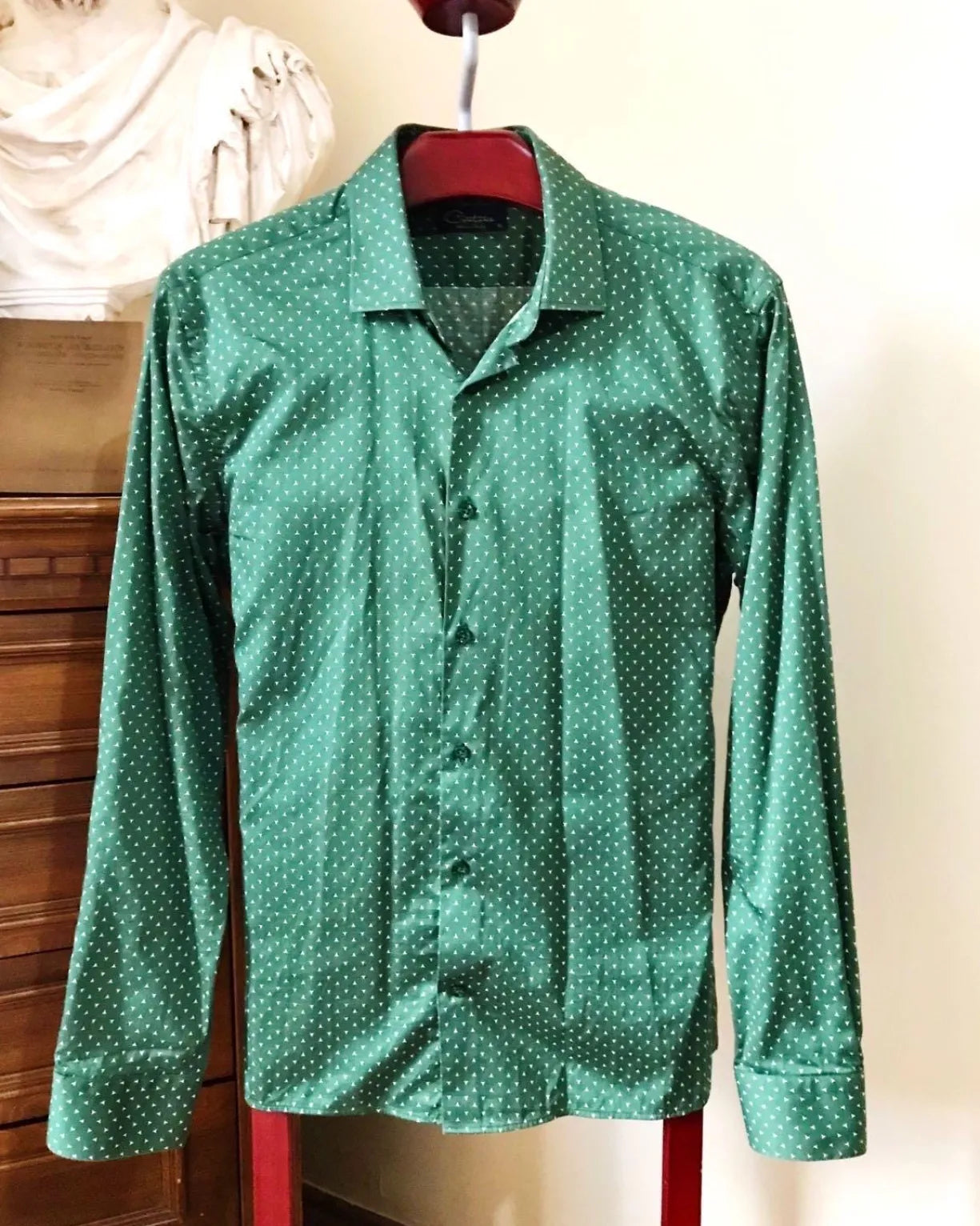 Green polka dot long sleeve shirt hanging on a red hanger