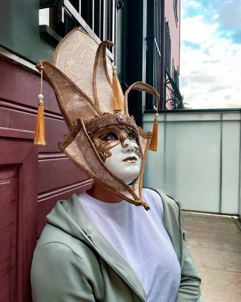 The Popess - Luxurious White and Gold Chic Art Venetian Mask, handcrafted for cosplay and masquerades, worn by an individual outdoors.